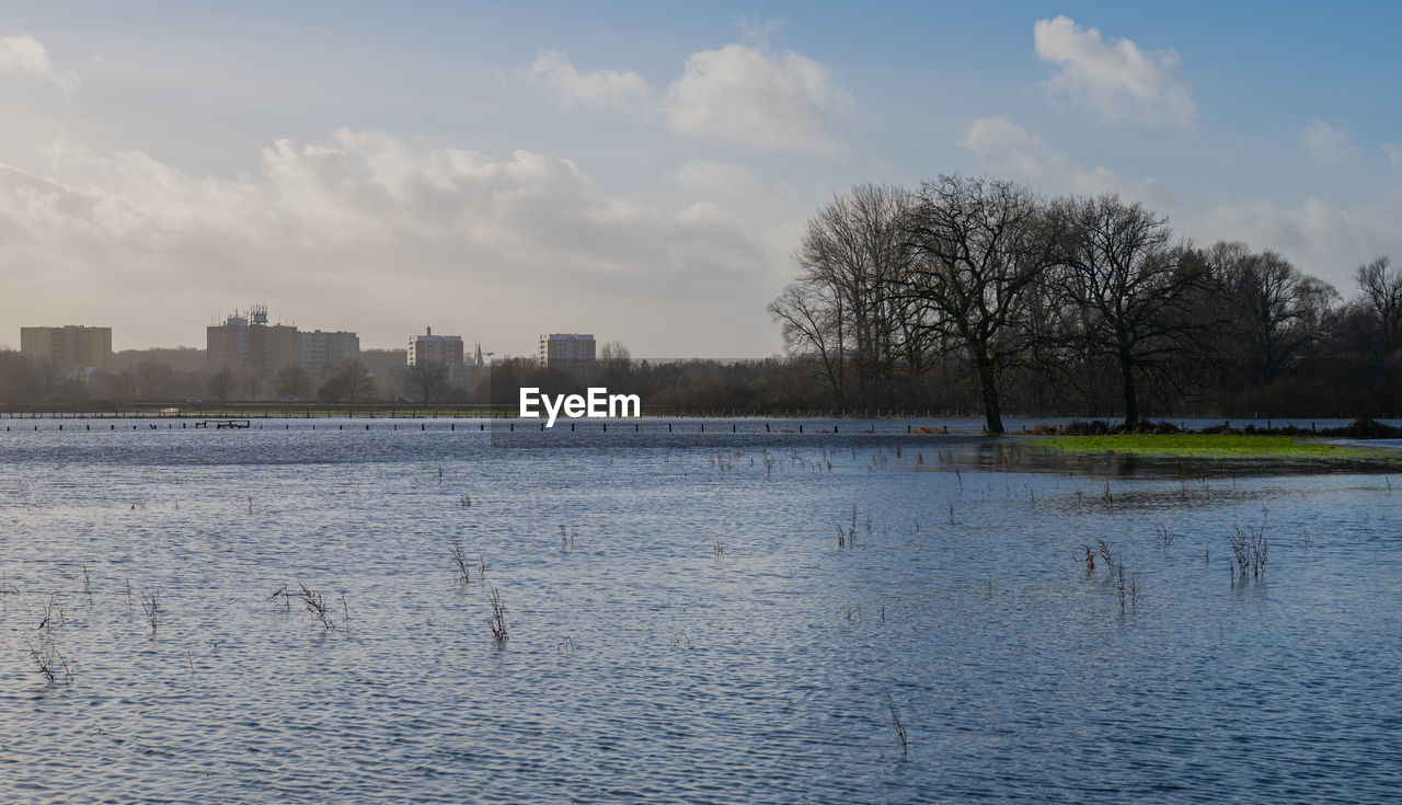 reflection, sky, winter, water, river, tree, nature, morning, architecture, cloud, landscape, snow, plant, building exterior, city, built structure, shore, no people, horizon, building, outdoors, environment, urban skyline, day, scenics - nature, beauty in nature, bare tree, tranquility, skyline, travel destinations, waterway, waterfront