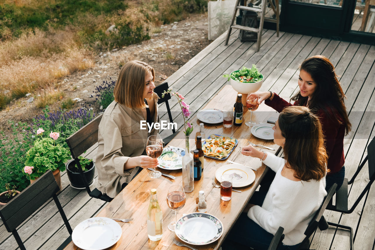 High angle view of female friends talking while enjoying meal at front yard