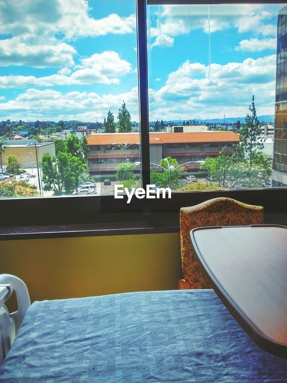 Buildings against cloudy sky seen through glass window