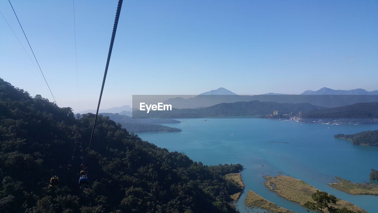 Scenic view of sea and mountains against clear blue sky