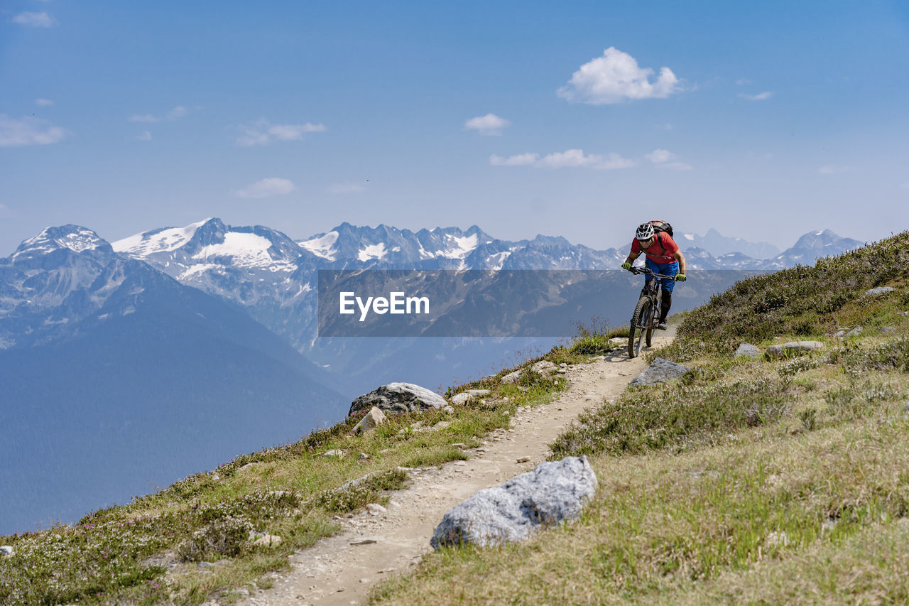 Man riding bicycle on mountain against sky