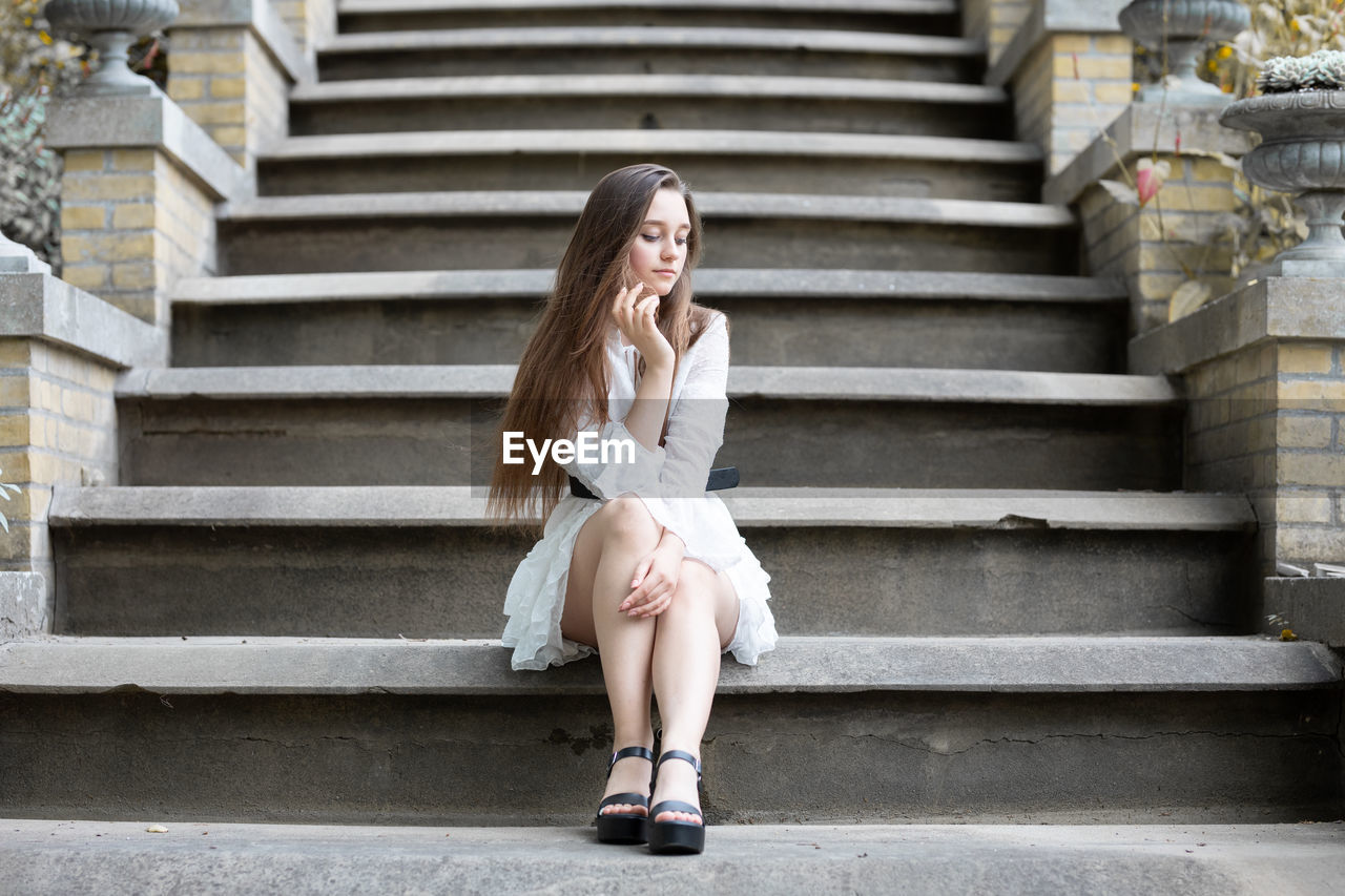 Full length of woman sitting on staircase