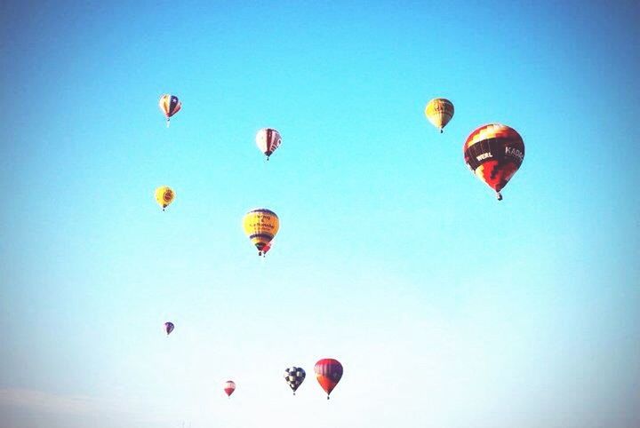 LOW ANGLE VIEW OF MULTI COLORED BALLOONS FLYING OVER BLUE SKY