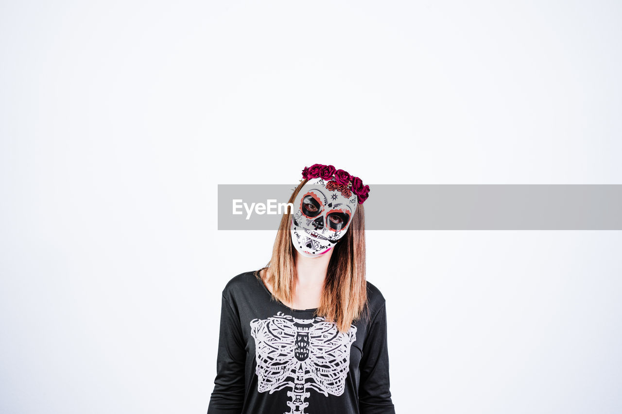 Woman wearing mask standing against white background