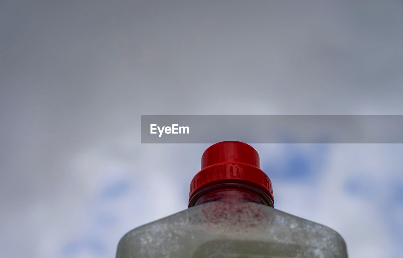 Low angle view of bottle against cloudy sky
