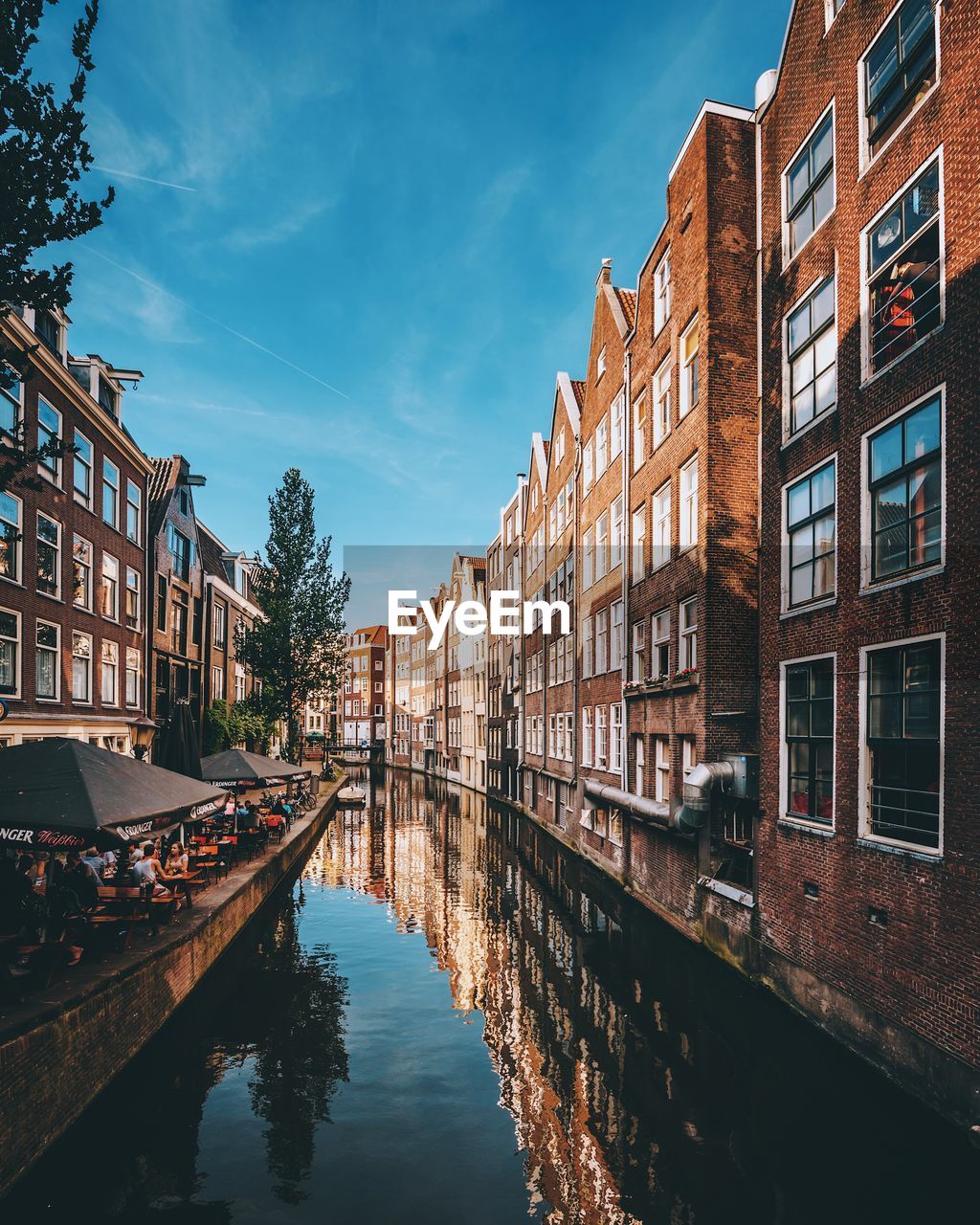 Canal amidst buildings in city against sky