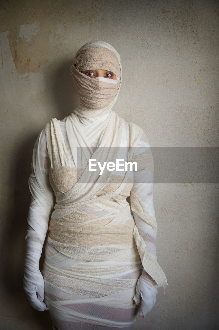 Portrait of woman wrapped with bandages against wall