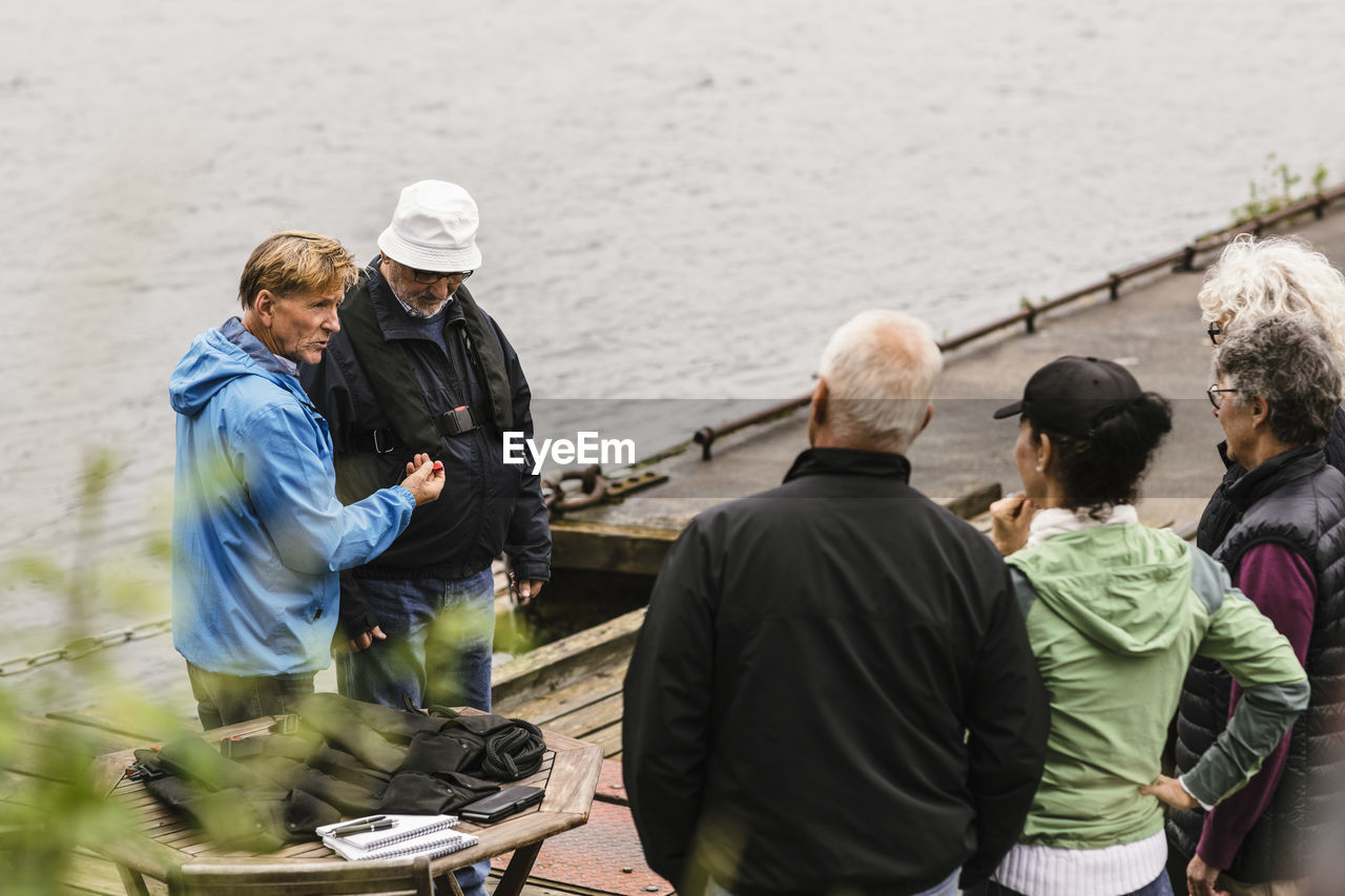 REAR VIEW OF PEOPLE STANDING ON SHORE