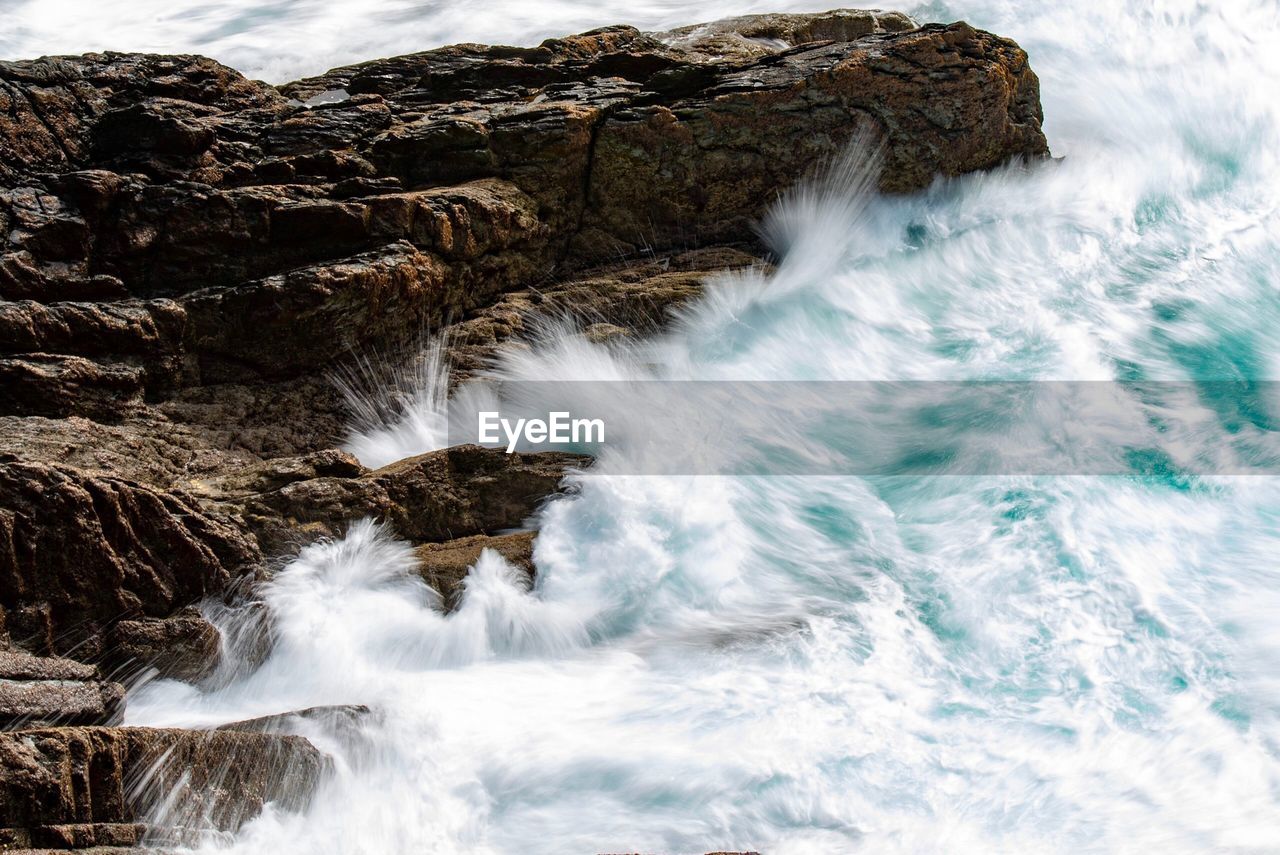 Scenic view of sea waves splashing against rocks