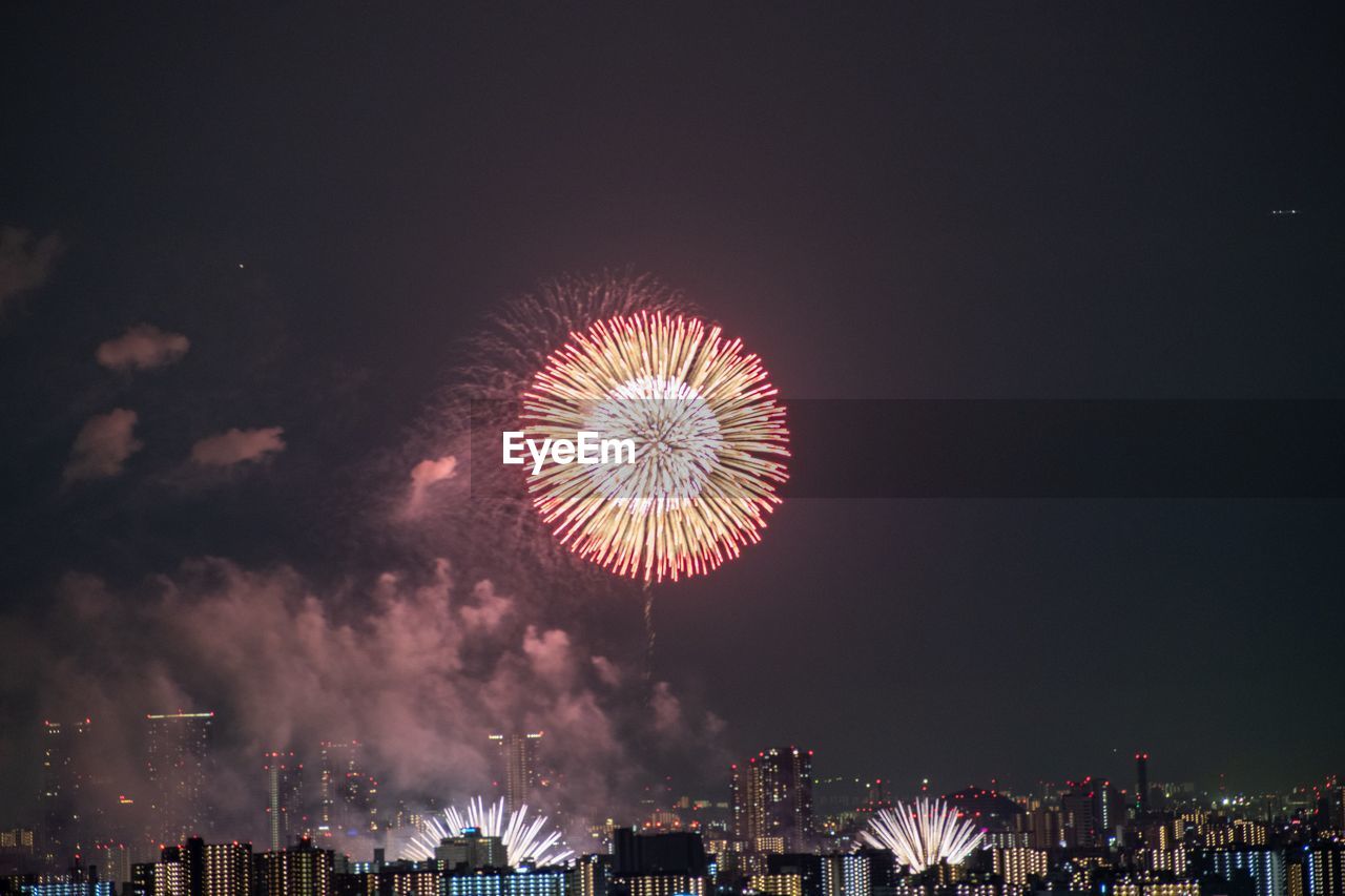 Low angle view of firework display in city against sky at night