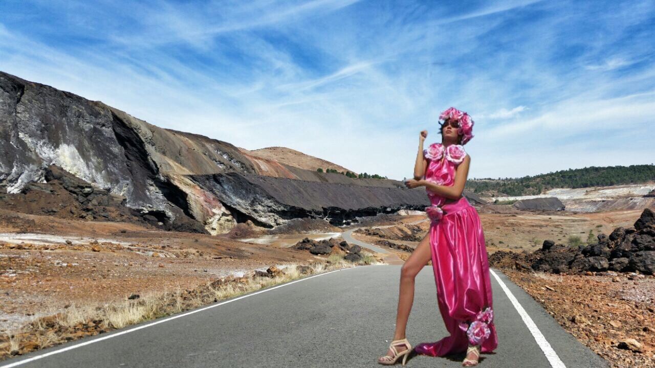 WOMAN STANDING ON ROAD AGAINST MOUNTAIN