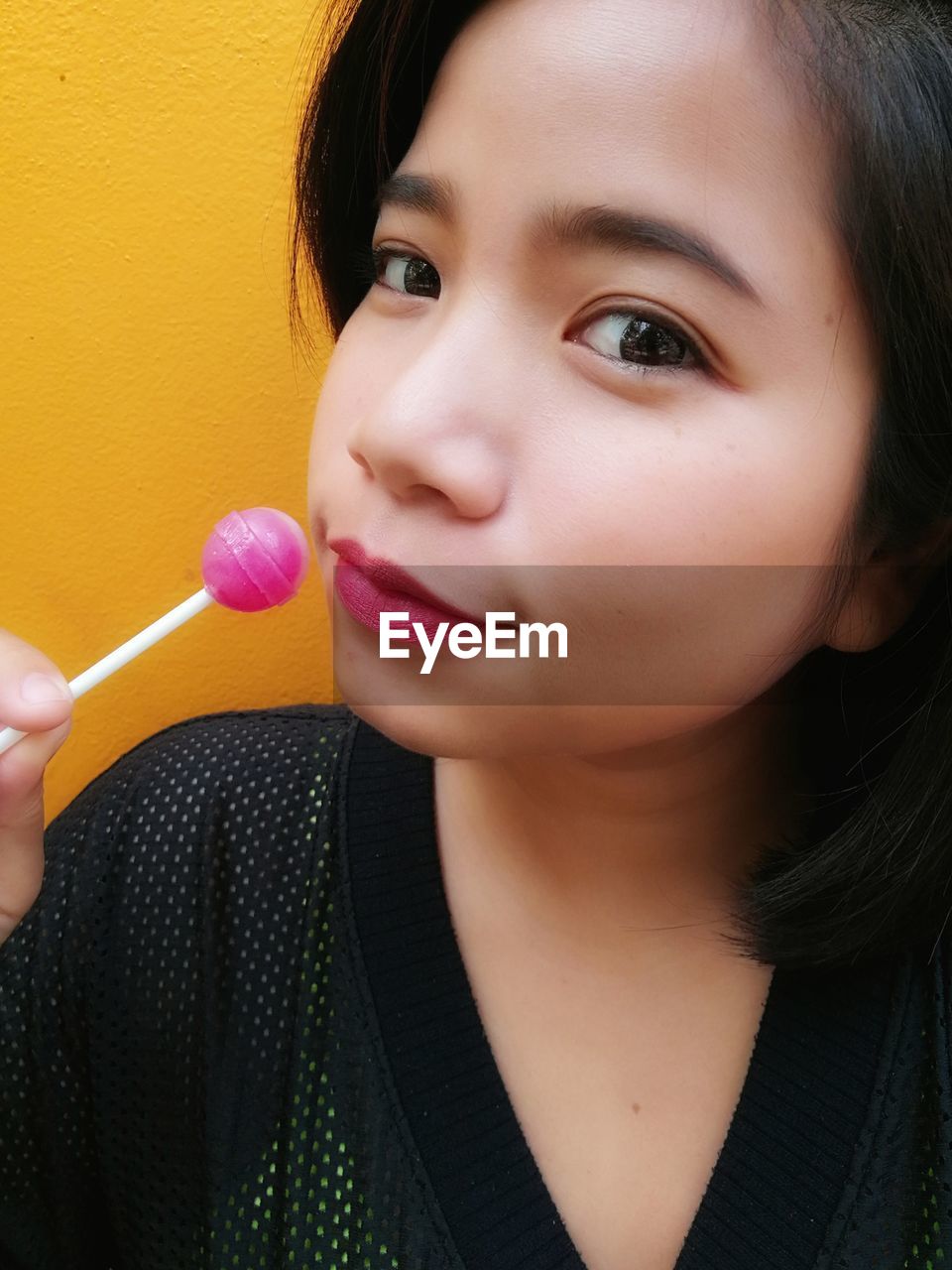 Close-up portrait of woman having pink lollipop