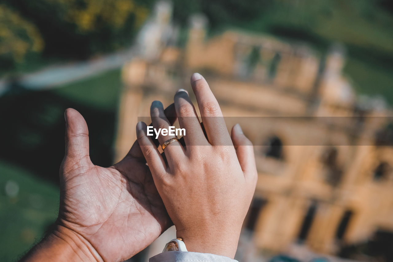 Cropped man holding hands of woman with historical building in background