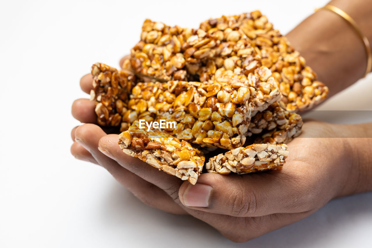 cropped hand of woman holding roasted coffee beans against white background