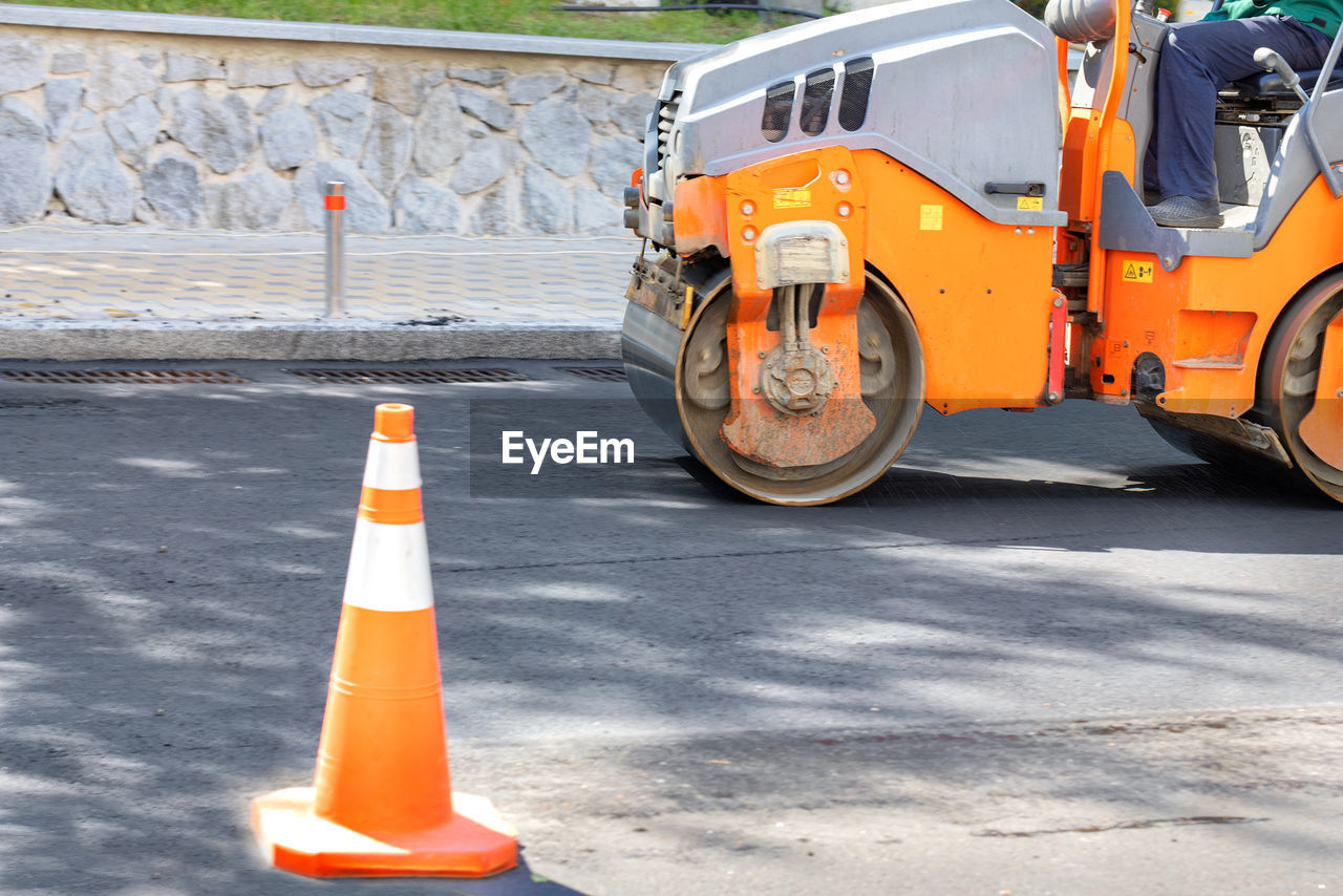 transportation, road, mode of transportation, traffic cone, cone, orange color, road construction, vehicle, construction industry, asphalt, street, city, sign, land vehicle, day, industry, transport, no people, wheel, motor vehicle, outdoors, yellow, architecture