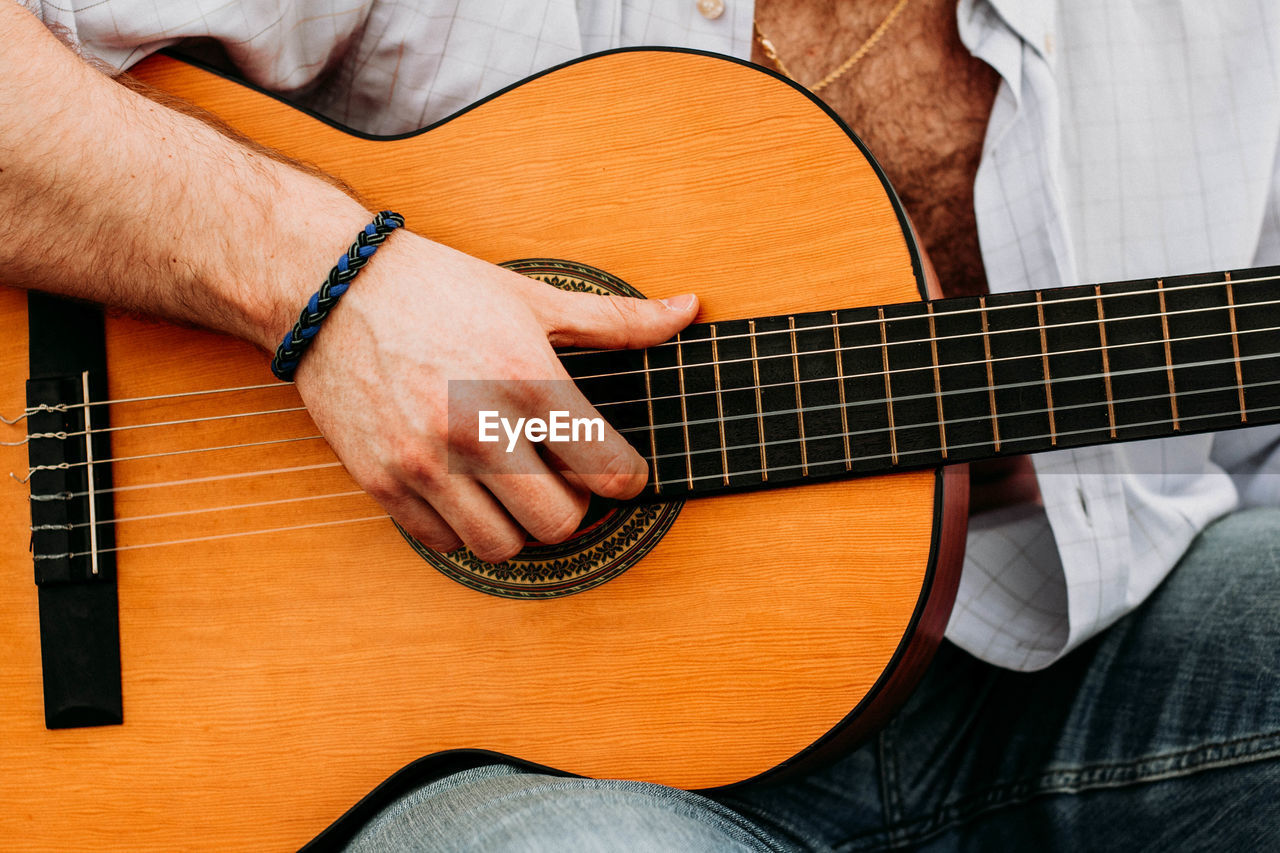 Midsection of man playing guitar