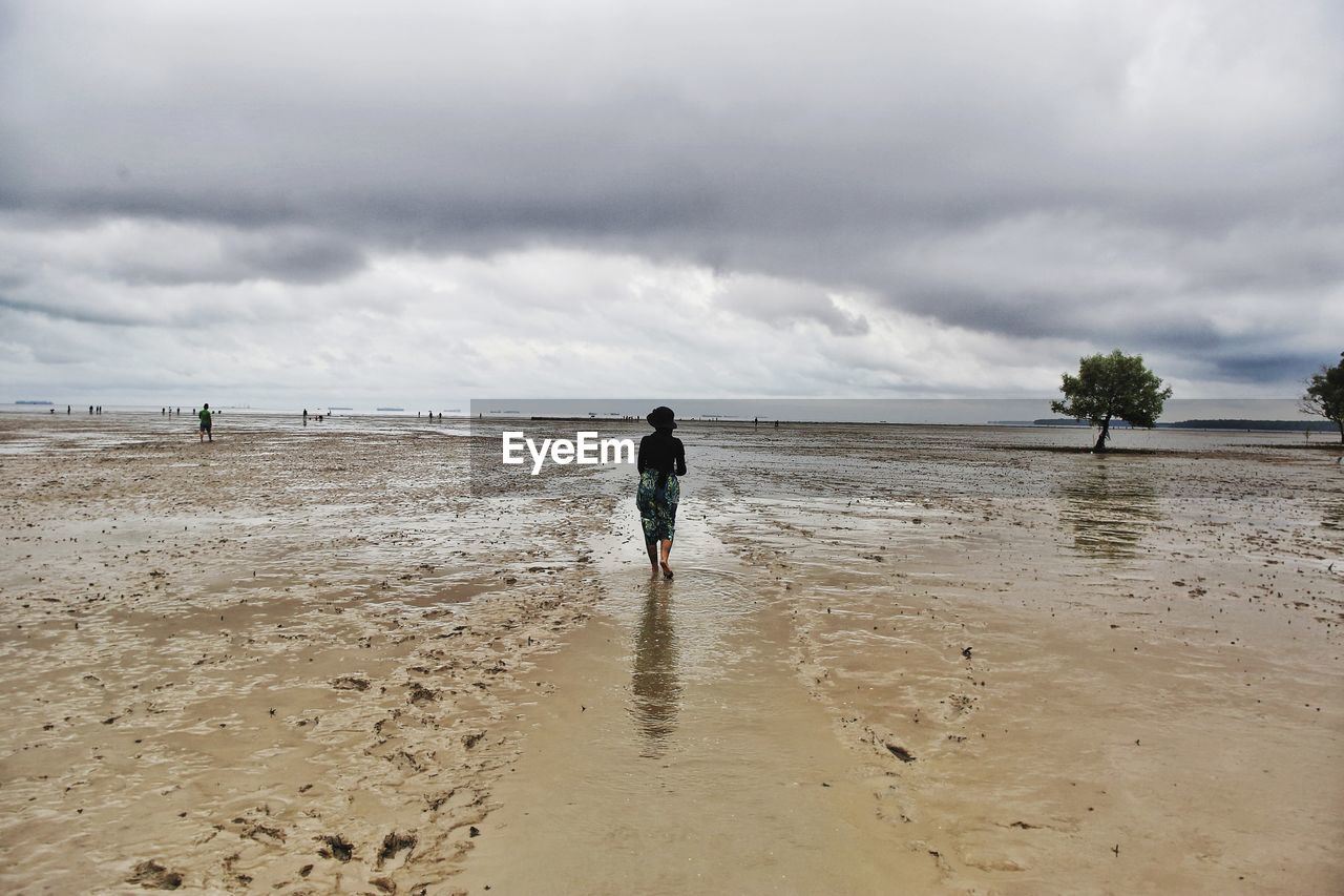 FULL LENGTH REAR VIEW OF MAN WALKING ON BEACH