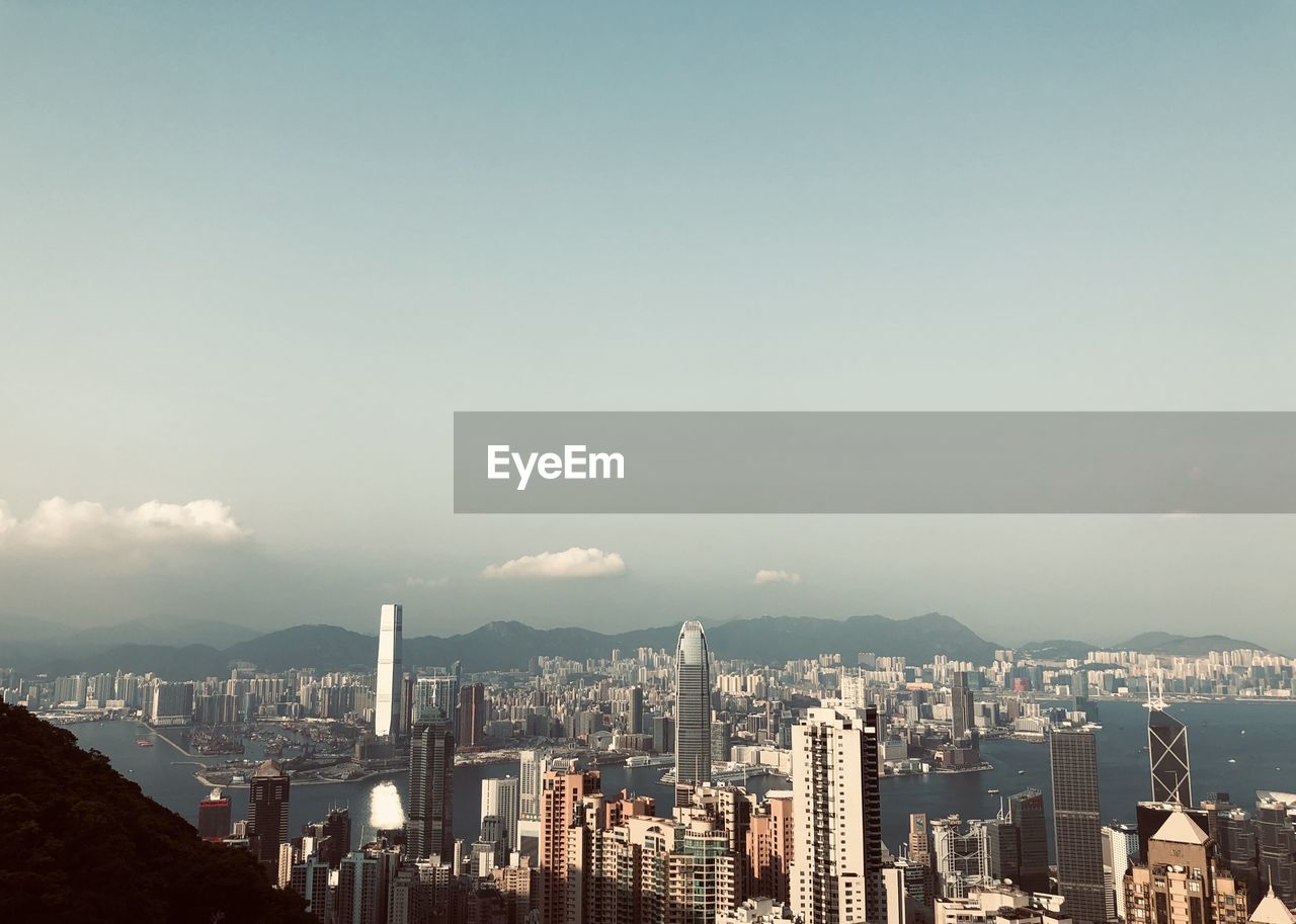 Aerial view of city buildings against cloudy sky