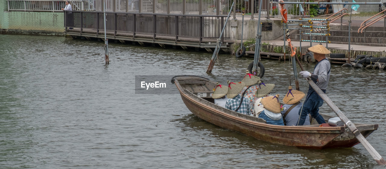 BOATS MOORED IN RIVER WITH BUILDINGS IN BACKGROUND