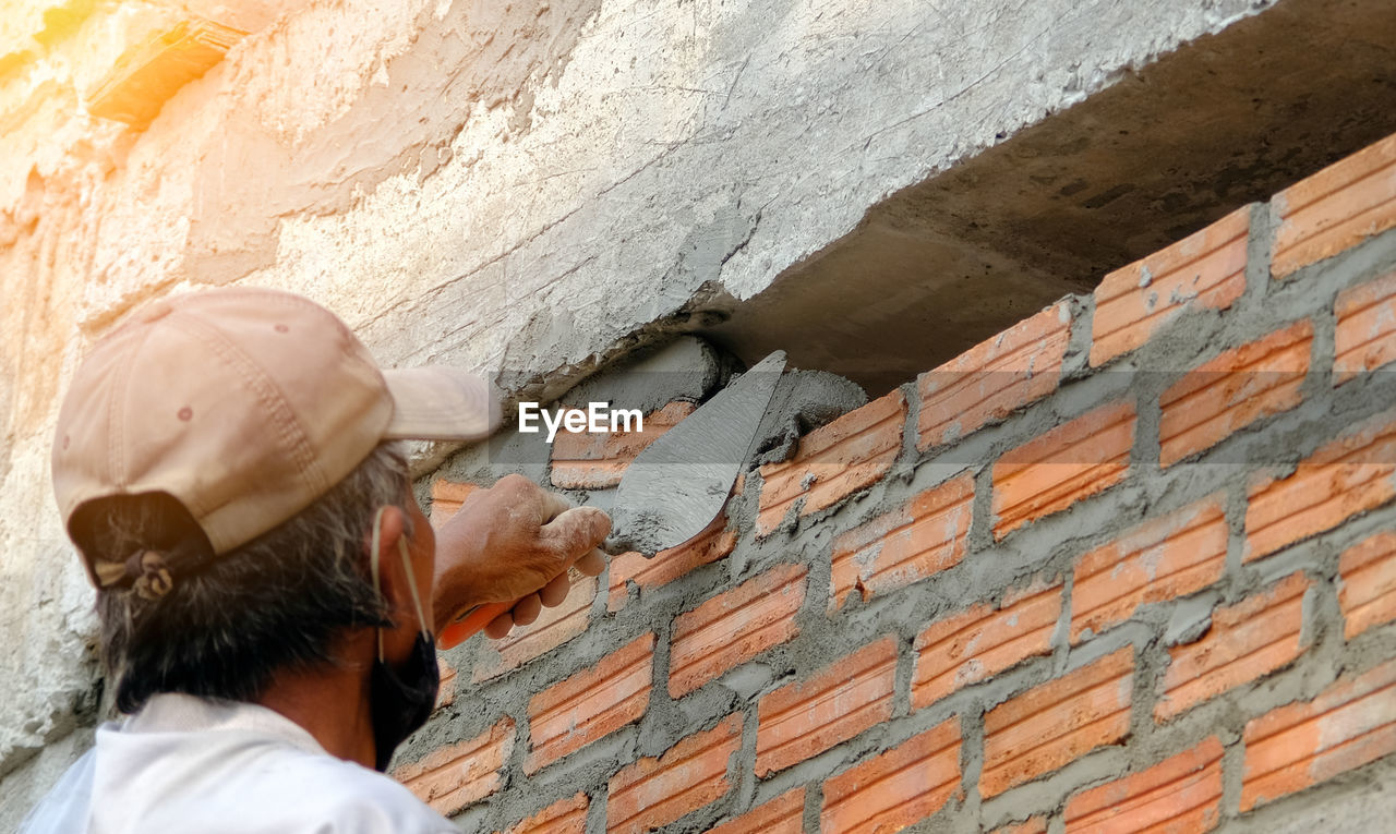Close up of industrial bricklayer installing bricks on construction site 