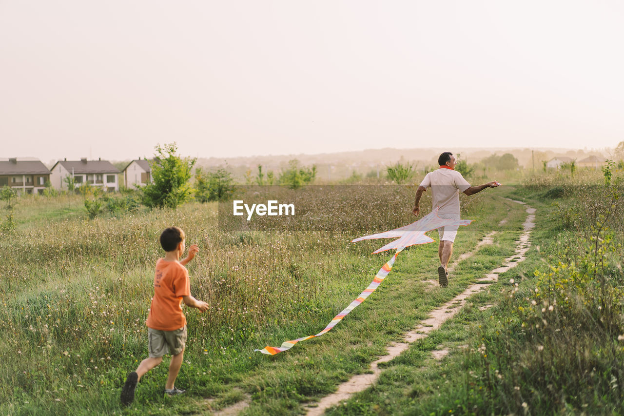 Happy family and children run on meadow with a kite in the summer on the nature.