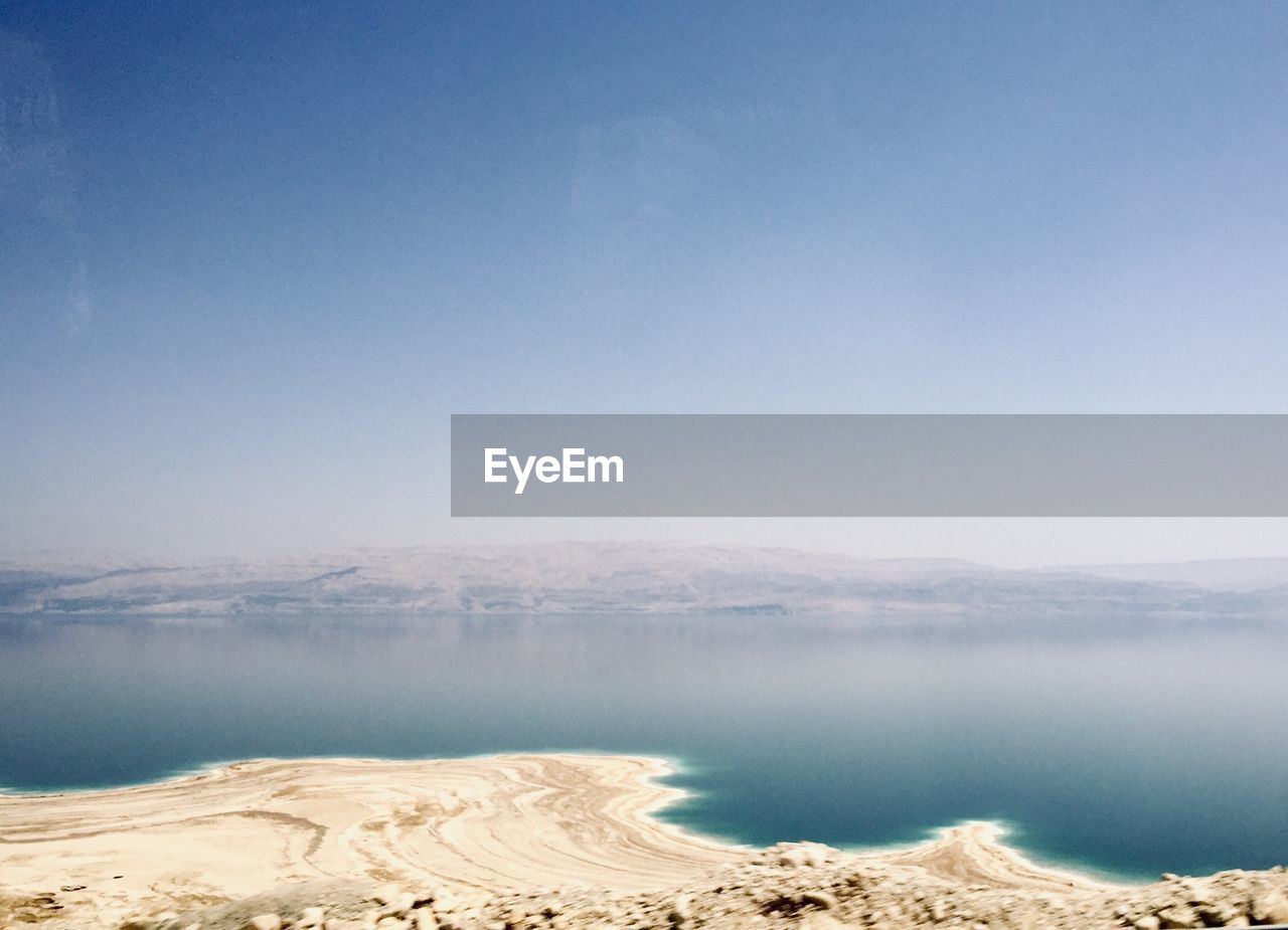 Scenic view of beach against clear blue sky