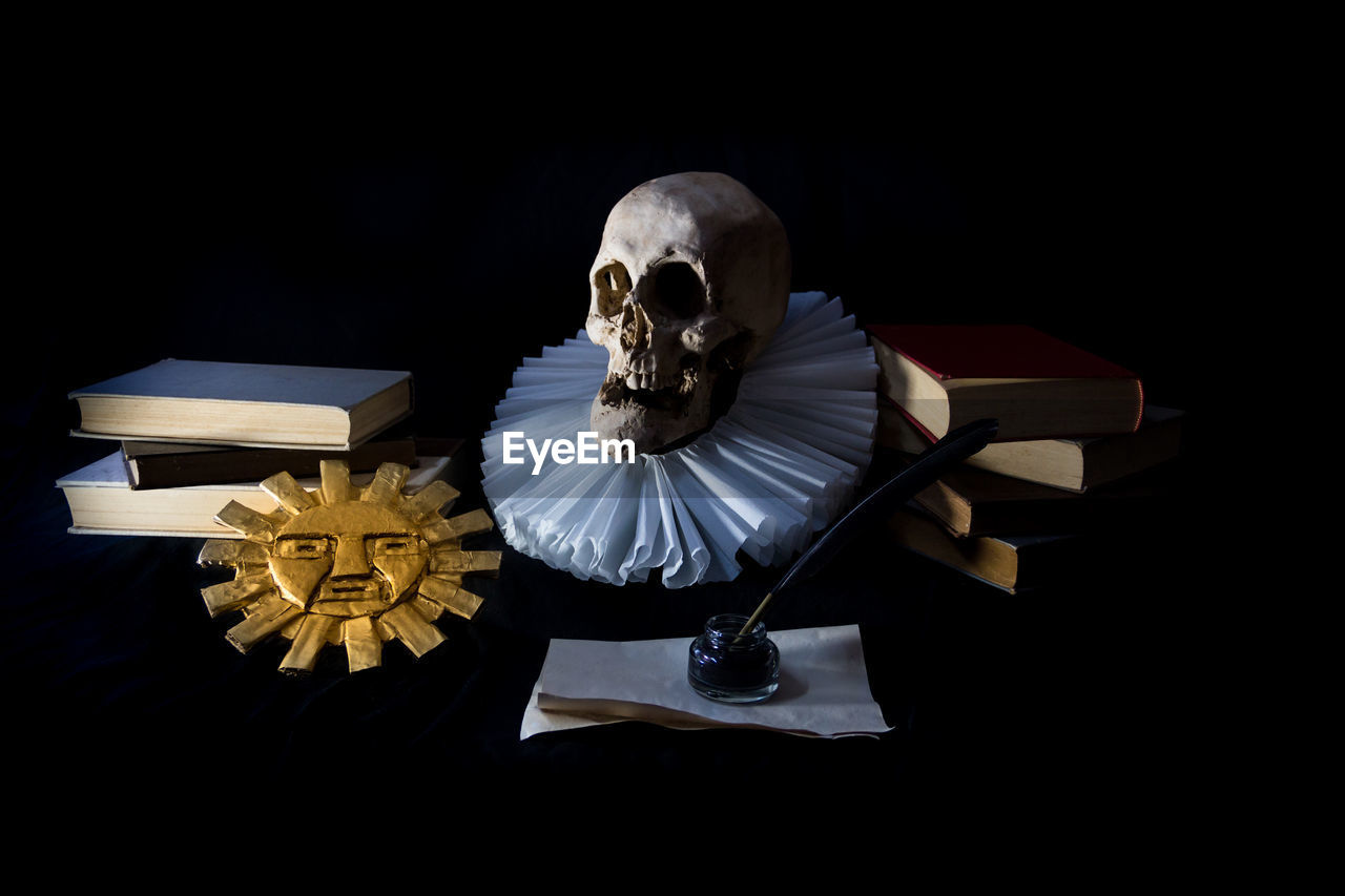black background, indoors, studio shot, darkness, bone, dark, one person, human skeleton, paper, death, adult