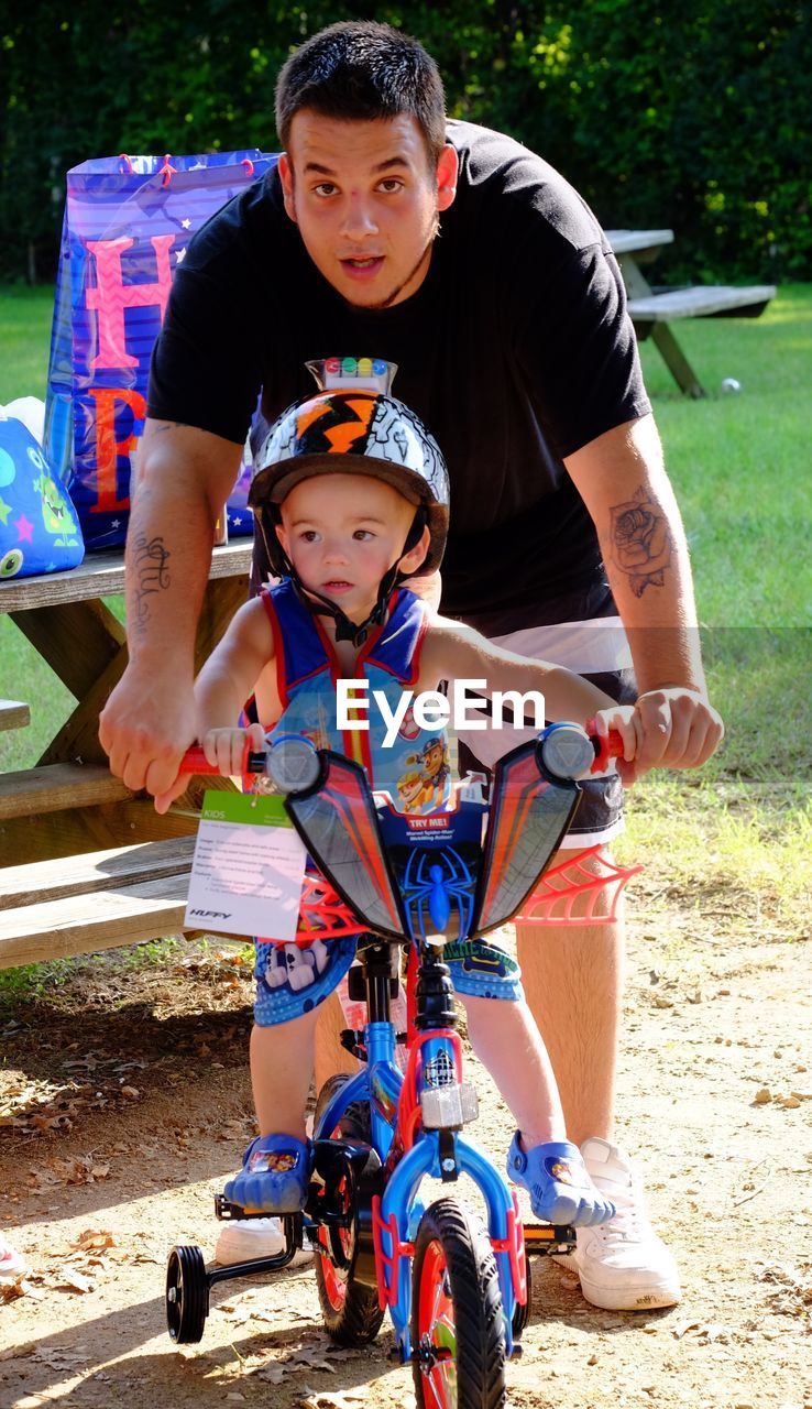 FULL LENGTH PORTRAIT OF HAPPY BOY RIDING WITH MAN