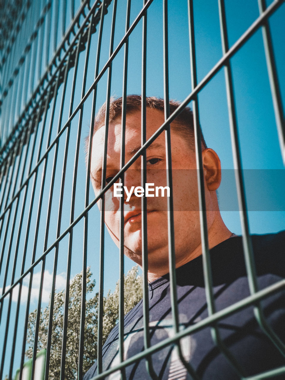 Low angle portrait of man seen through fence