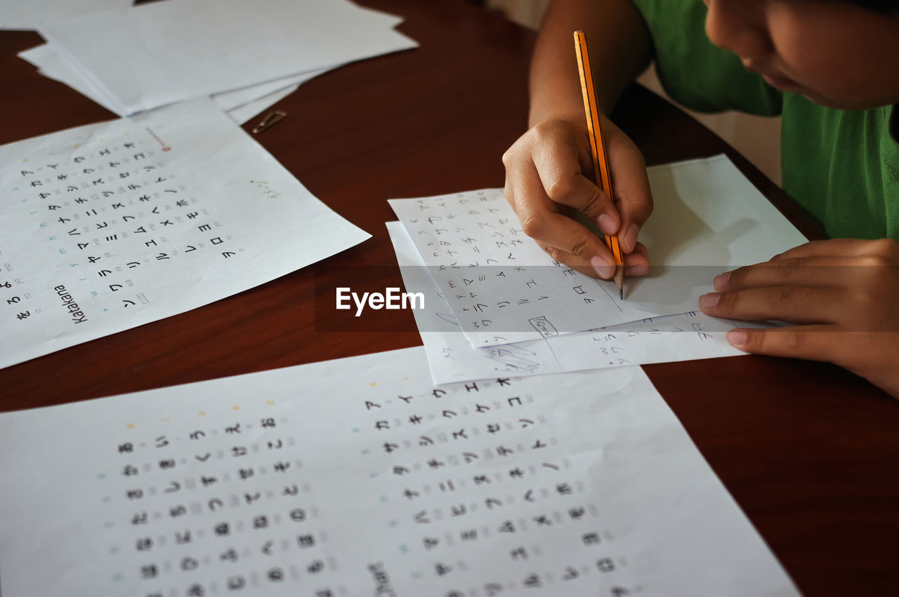 Midsection of boy writing on paper at home