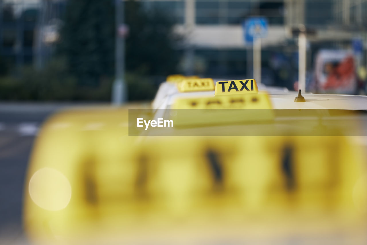 Selective focus on taxi sign on roof. car waiting for passenger in city street.