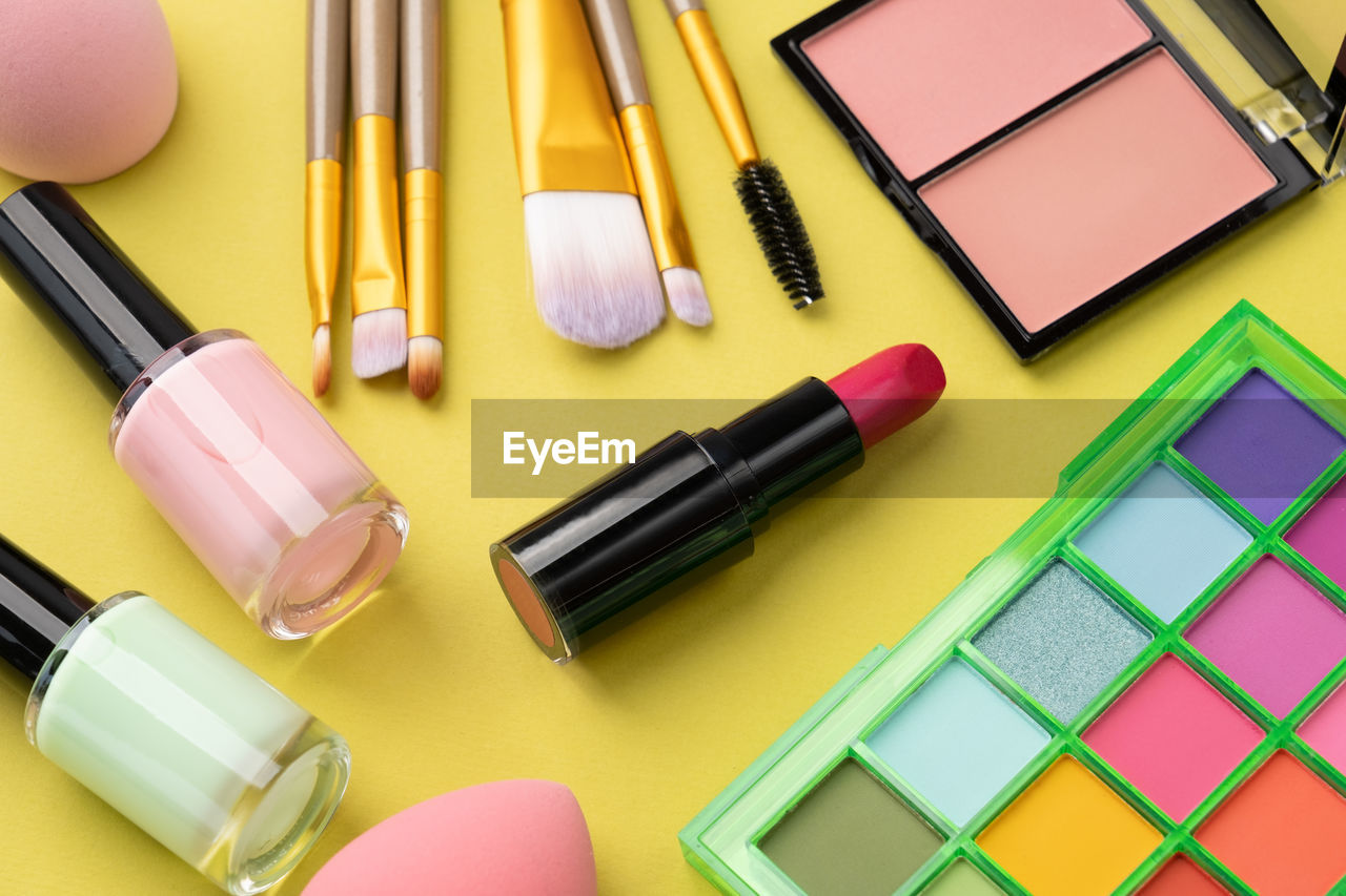 Bright summer eyeshadow palette and makeup products on green background. makeup cosmetics