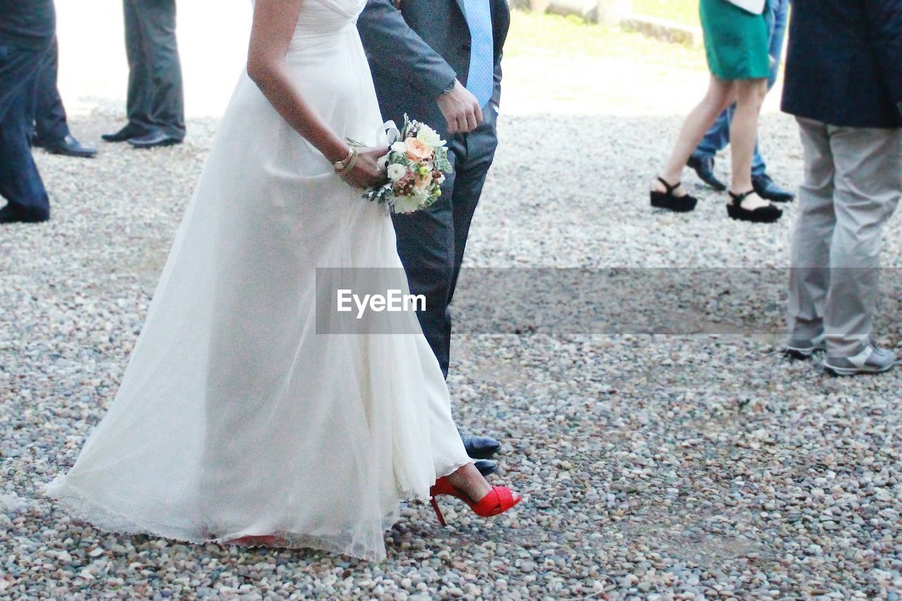 Low section of bride and groom walking on street during wedding