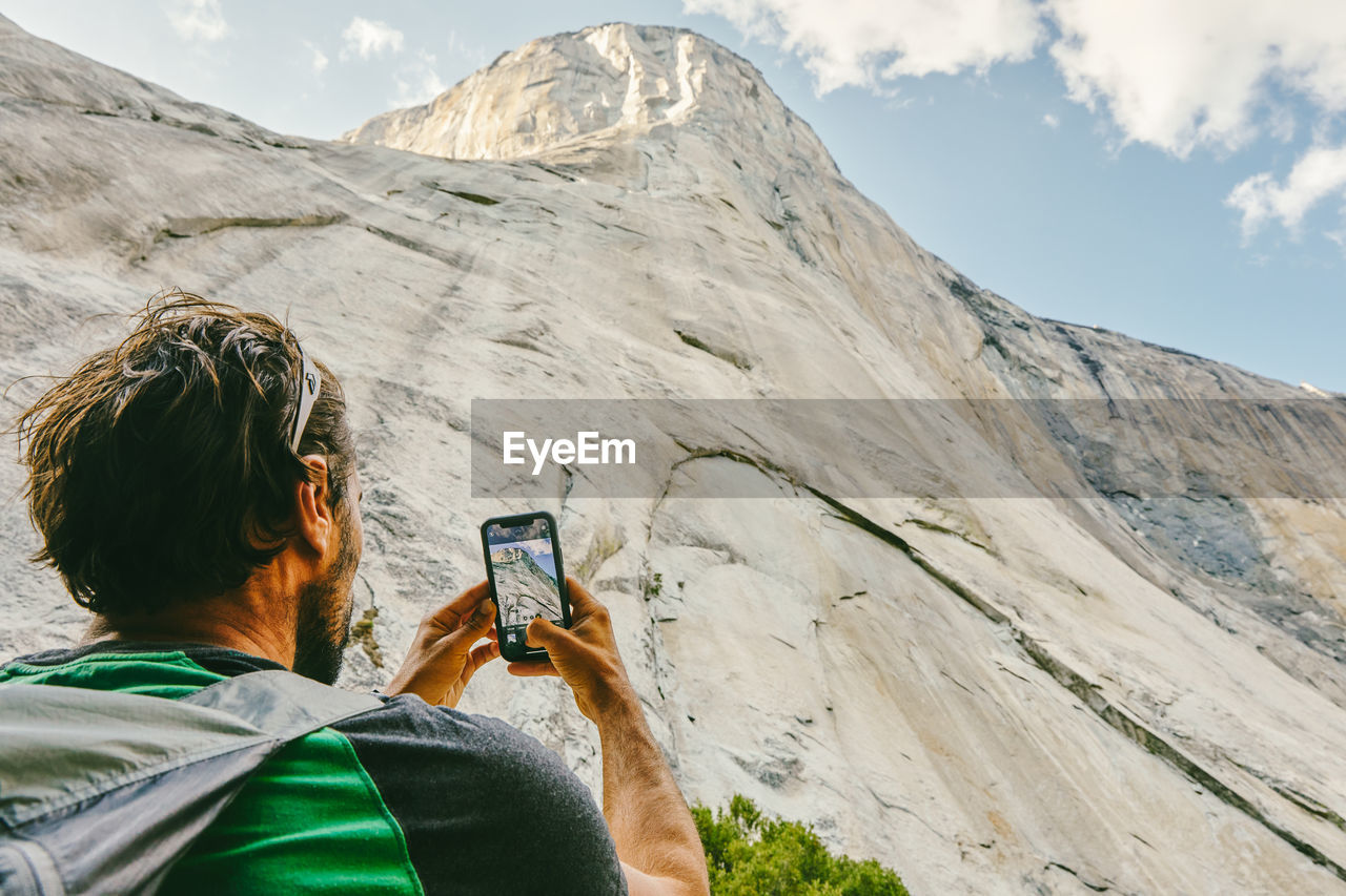 Young man taking picture of el capitan mountain in yosemite park.