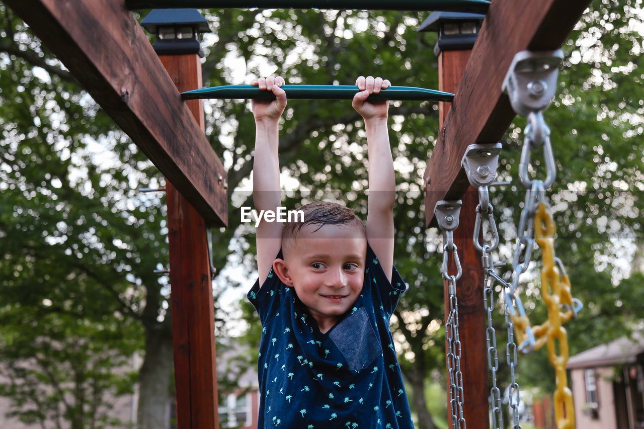 Smiling boy hanging on monkey bars