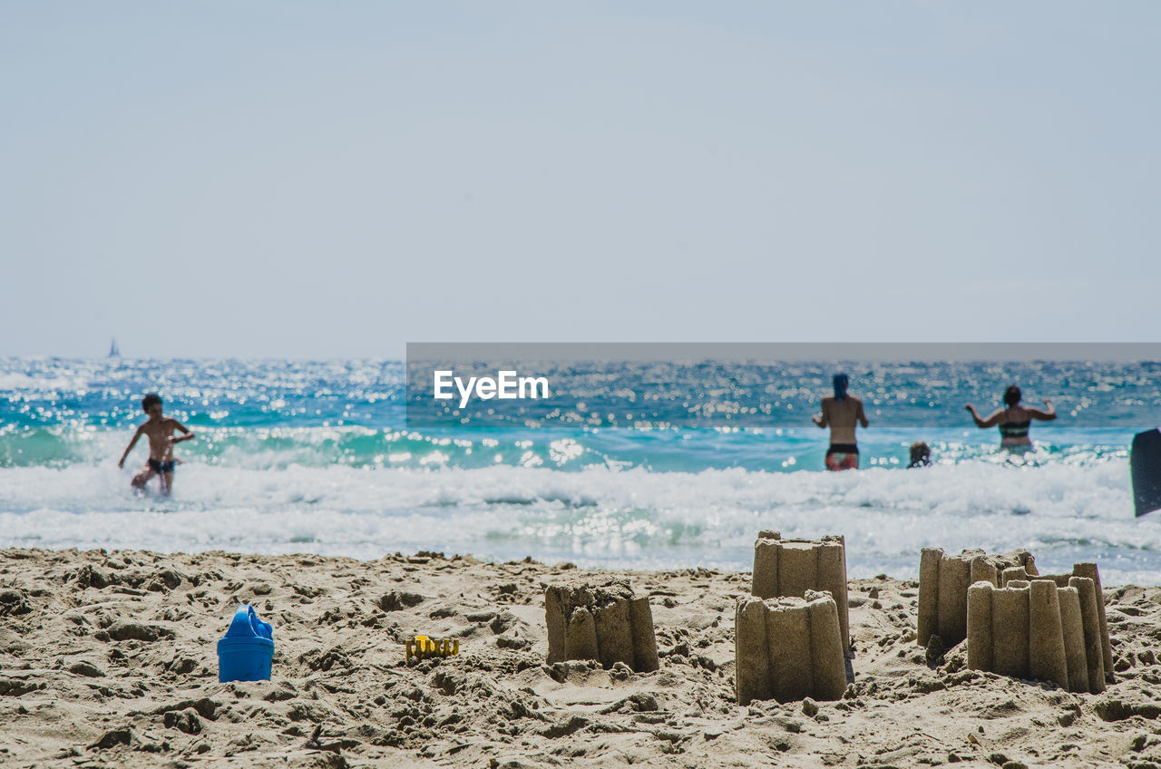 People swimming in ocean against clear sky