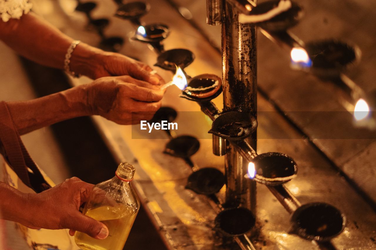 Cropped hands of people igniting diyas