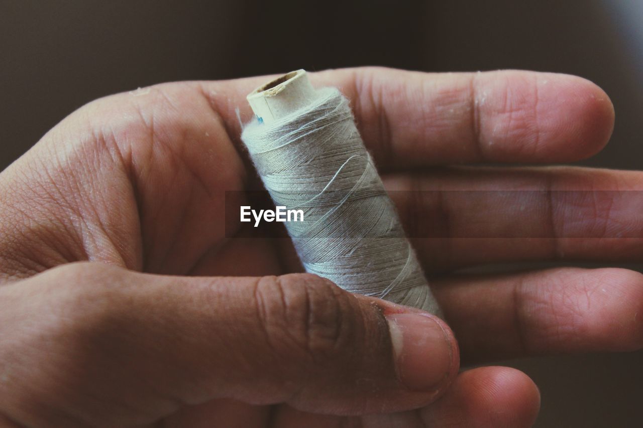 Close-up of hand holding thread spool