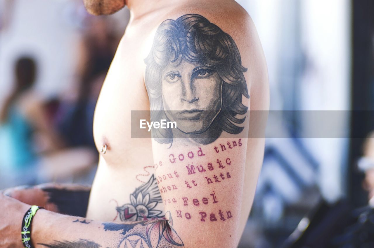 Side view of shirtless man with jim morrison tattoo on shoulder