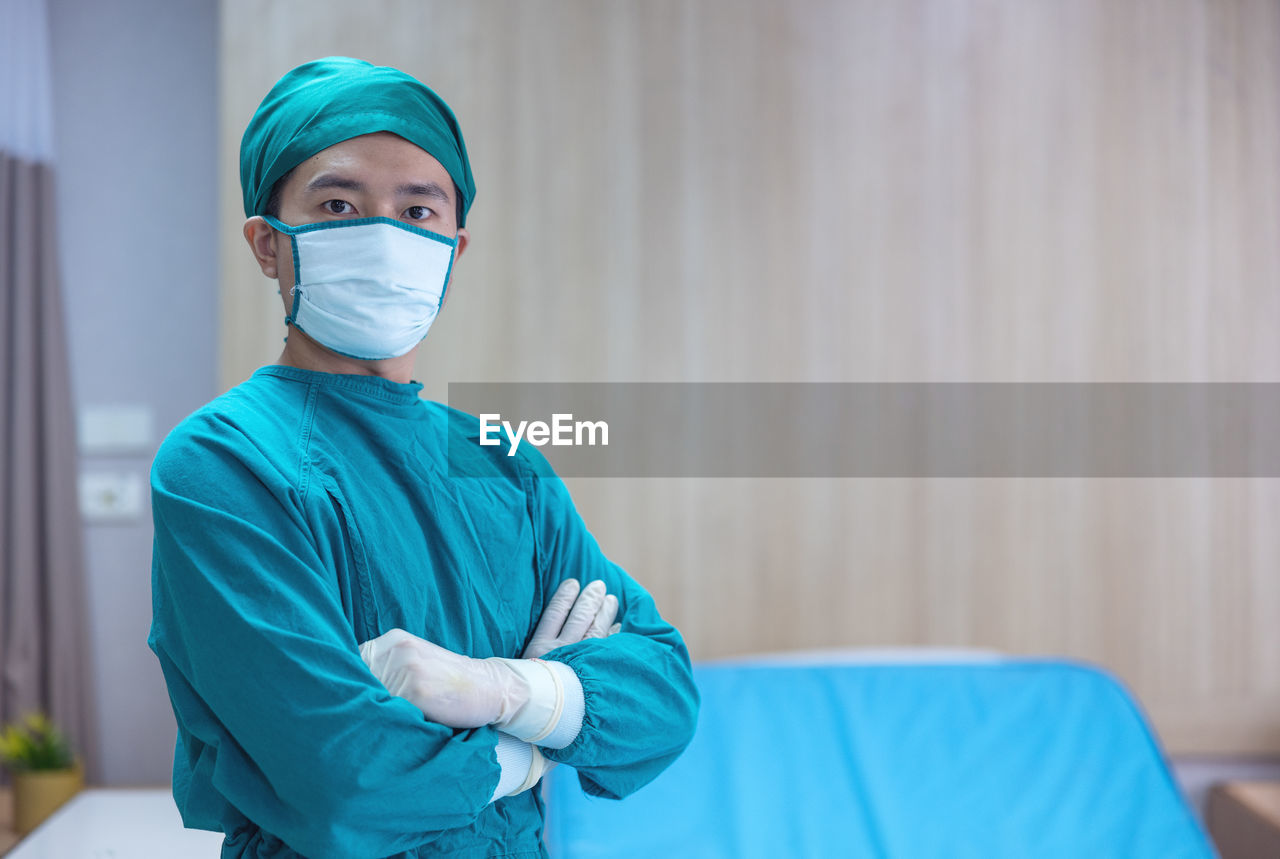 Portrait of a male surgeon in an operating room with a team of doctors in the background.