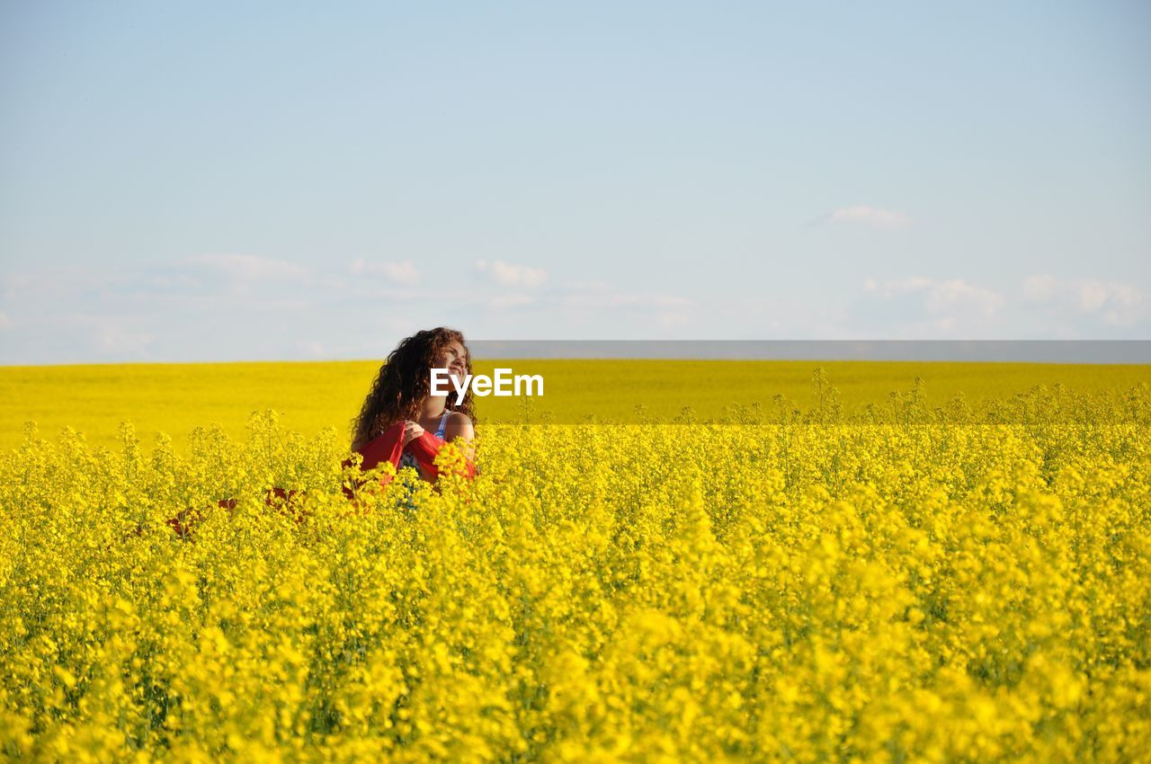 Teenage girl in oilseed rape field against sky
