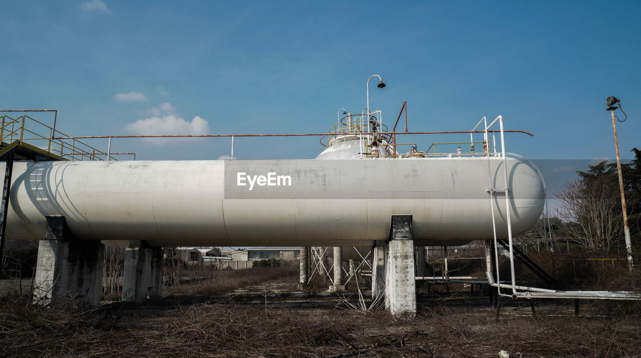 Storage tank at industry against sky