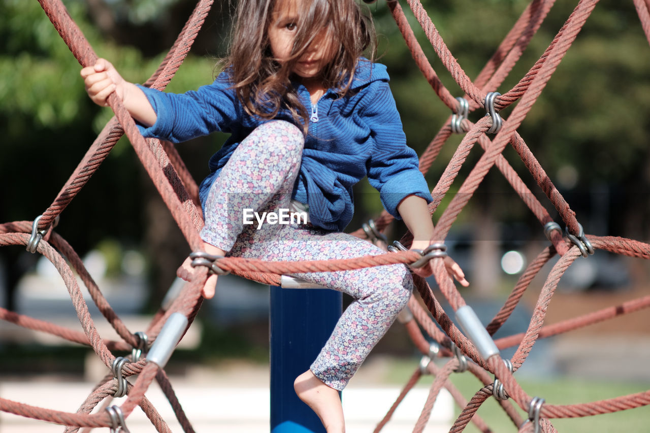 Portrait of girl climbing rope at park