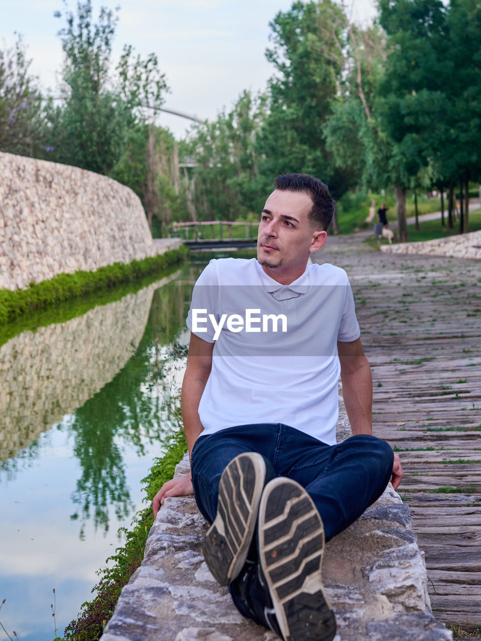 Portrait of young man sitting on rock by lake