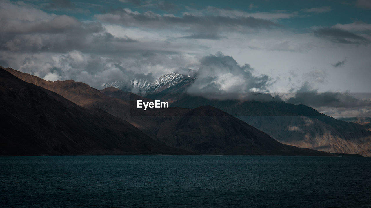 Scenic view of sea by mountains against sky