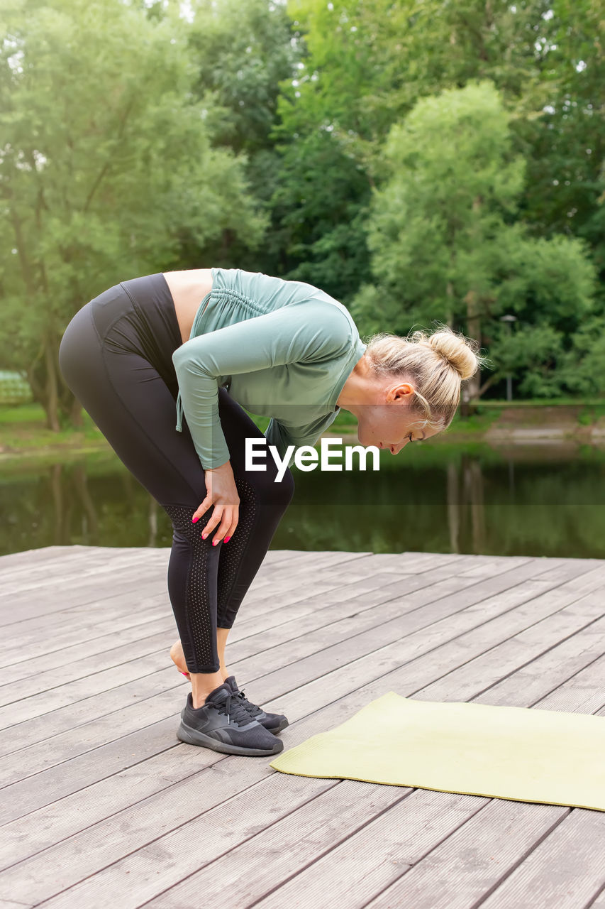 A woman taking off her black sneakers in front of a green sports mat