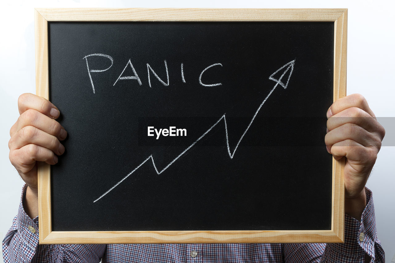 MIDSECTION OF MAN HOLDING TEXT ON SHELF