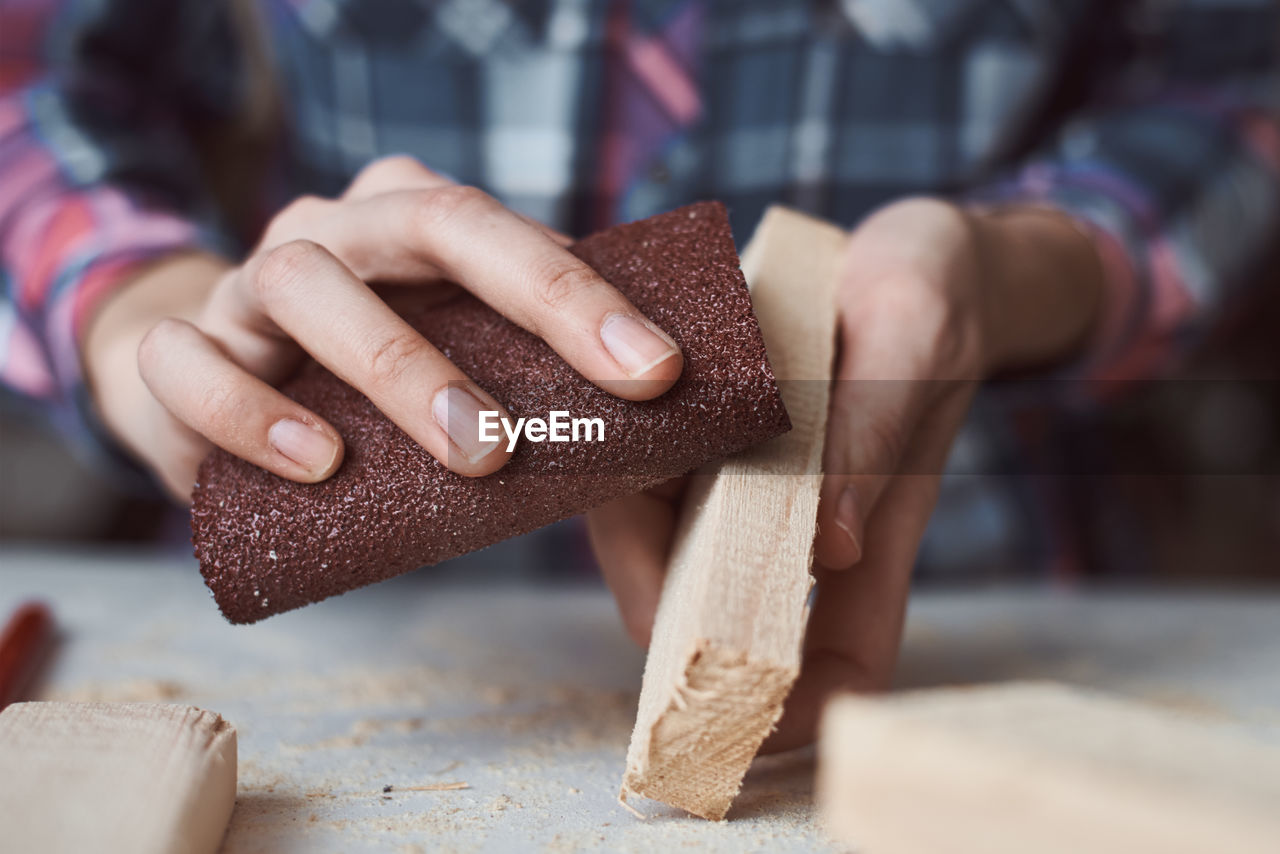 Carpenter hands polishing wooden planks with sandpaper. concept of diy woodwork and furniture making