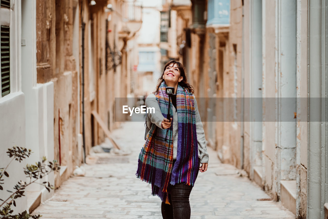 Woman holding monopod standing in alley