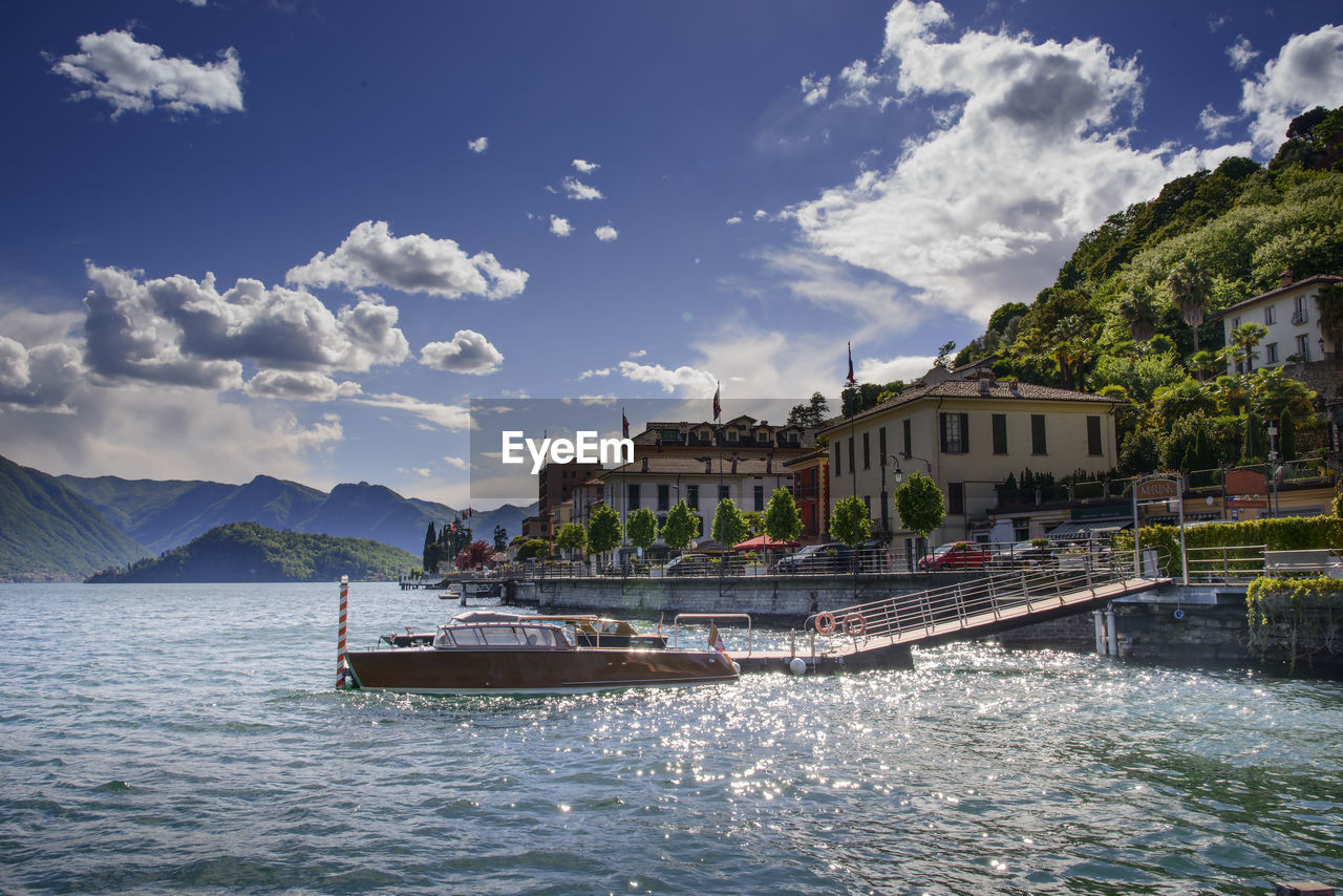 BOATS ON SEA BY BUILDINGS IN CITY AGAINST SKY